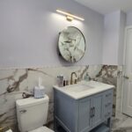Finished bathroom remodel with gray vanity and marble backsplash