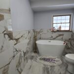 Finished bathroom remodel with freestanding tub and marble-look tile